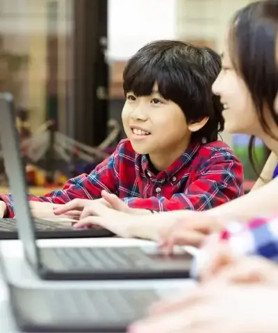 A boy with red shirt is learning python coding with his sister at centre