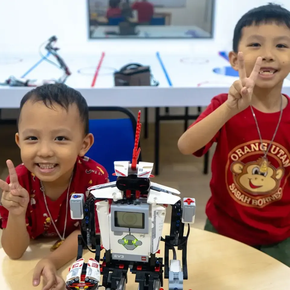 Young children building a LEGO robot together at a classroom table