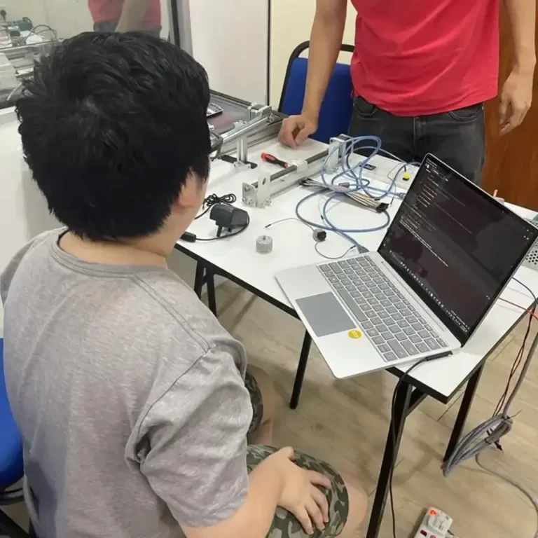 young boy doing Arduino coding with laptop to control conveyor