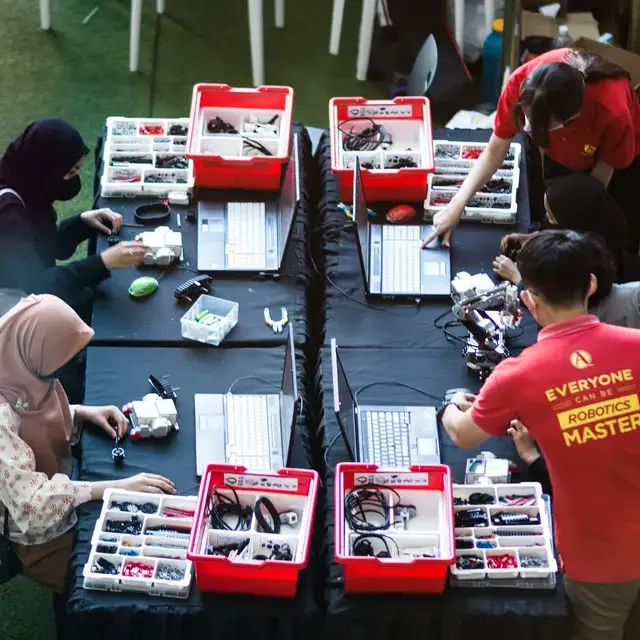 Teachers who wearing red Advaspire shirt is teaching kids how to build lego robot at Melawati Mall
