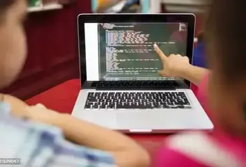 teacher is pointing on laptop screen to show students which line of coding is having bugs