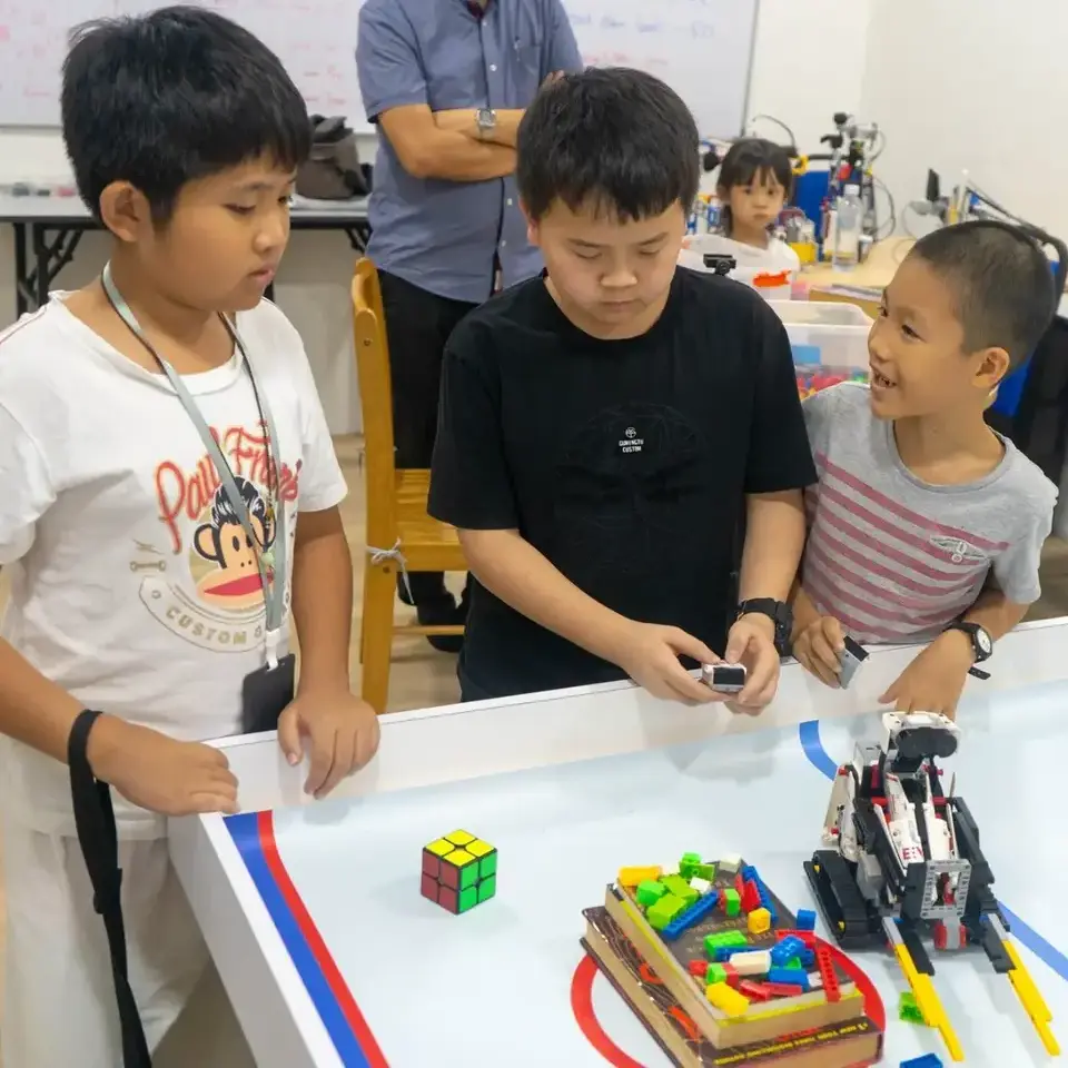 3 little boys in a team using a remote to instruct the lego robot to complete mission happily at Semenyih Advaspire centre